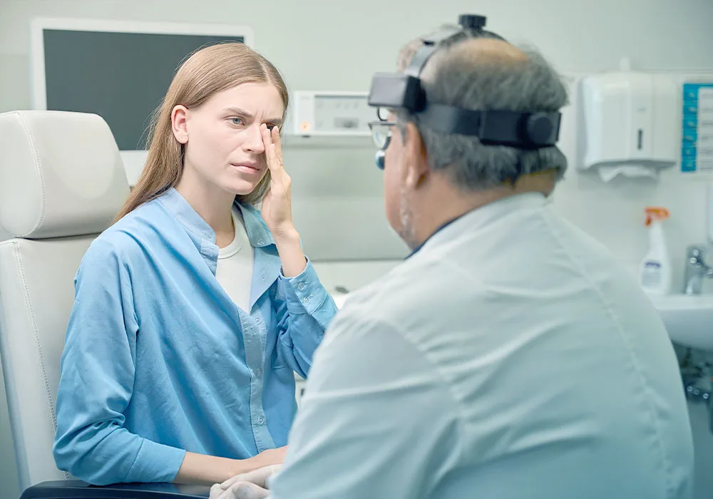 A young woman consulting an ophthalmologist and describing eye discomfort during a pre-LASIK evaluation.